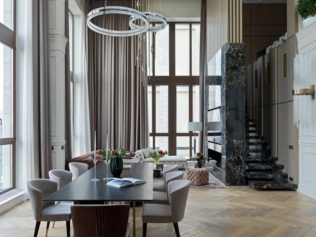 Phòng khách Penthouse Gia Lâm thông tầng với rèm cao, cụm đèn vòng và cầu thang vân đá