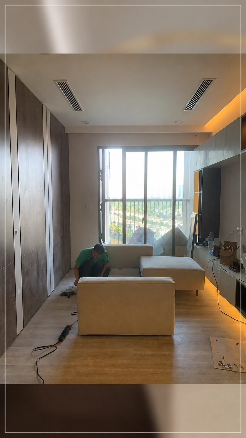 Thợ thao tác lắp sofa trong phòng khách cạnh cửa ban công